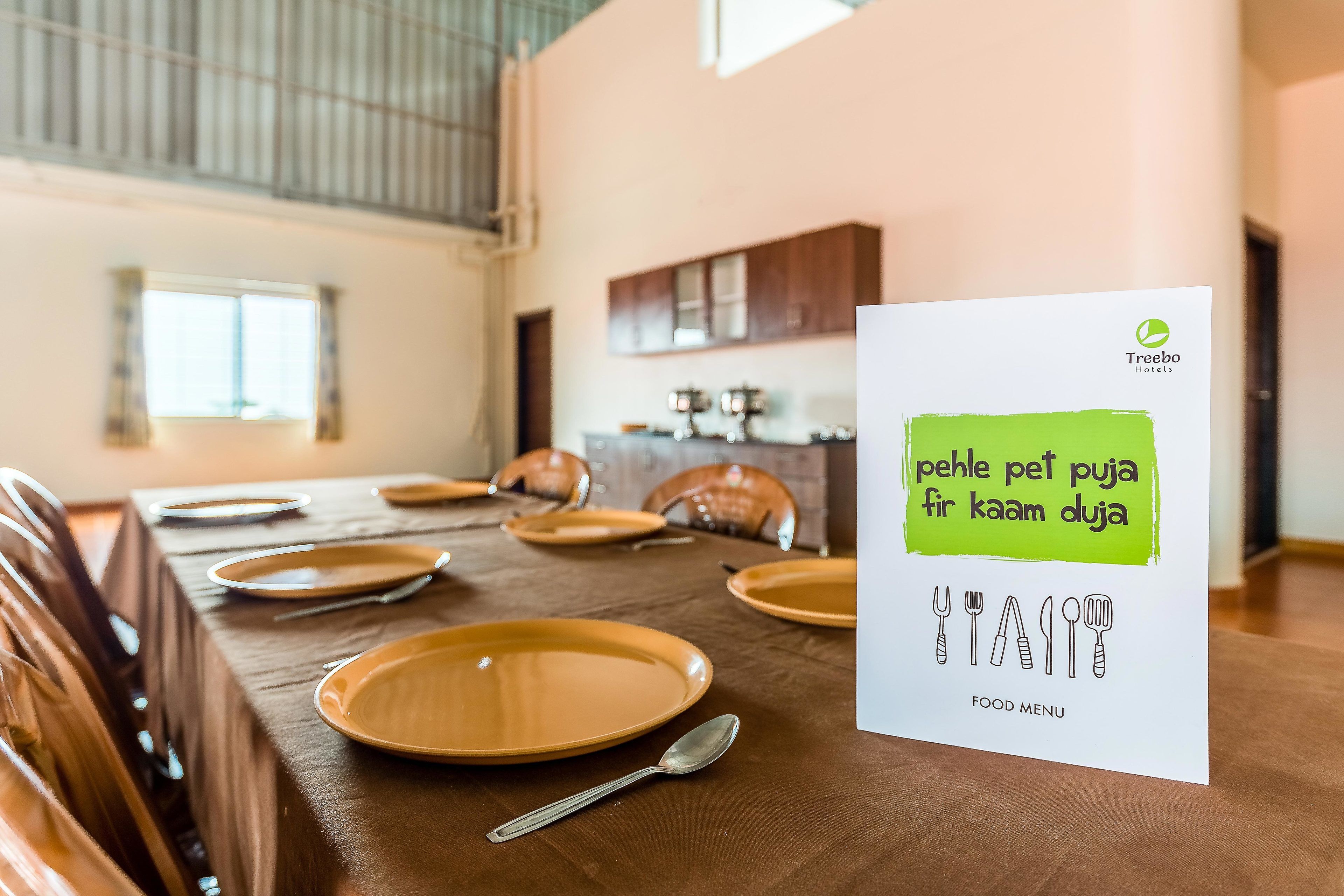 A dining table set with plates and cutlery, a spoon, and a menu sign with a green highlight.