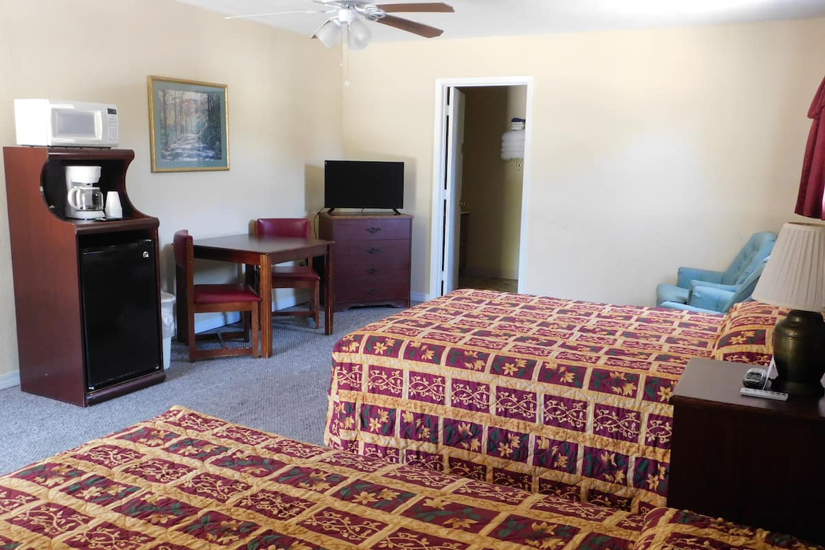 A hotel room with a bed, a desk, a chair, a television, a microwave, and a coffee maker.