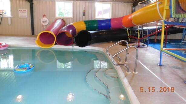 An indoor pool with a colorful slide and a metal ladder. - Little Shamrock Motel A1 (Murfreesboro)