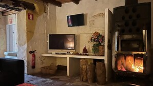 Una habitación rústica con chimenea de piedra, televisor y extintor.