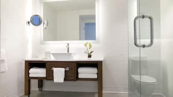 Un bagno moderno con un lavandino bianco, un mobile bagno in legno, uno specchio e un box doccia in vetro.