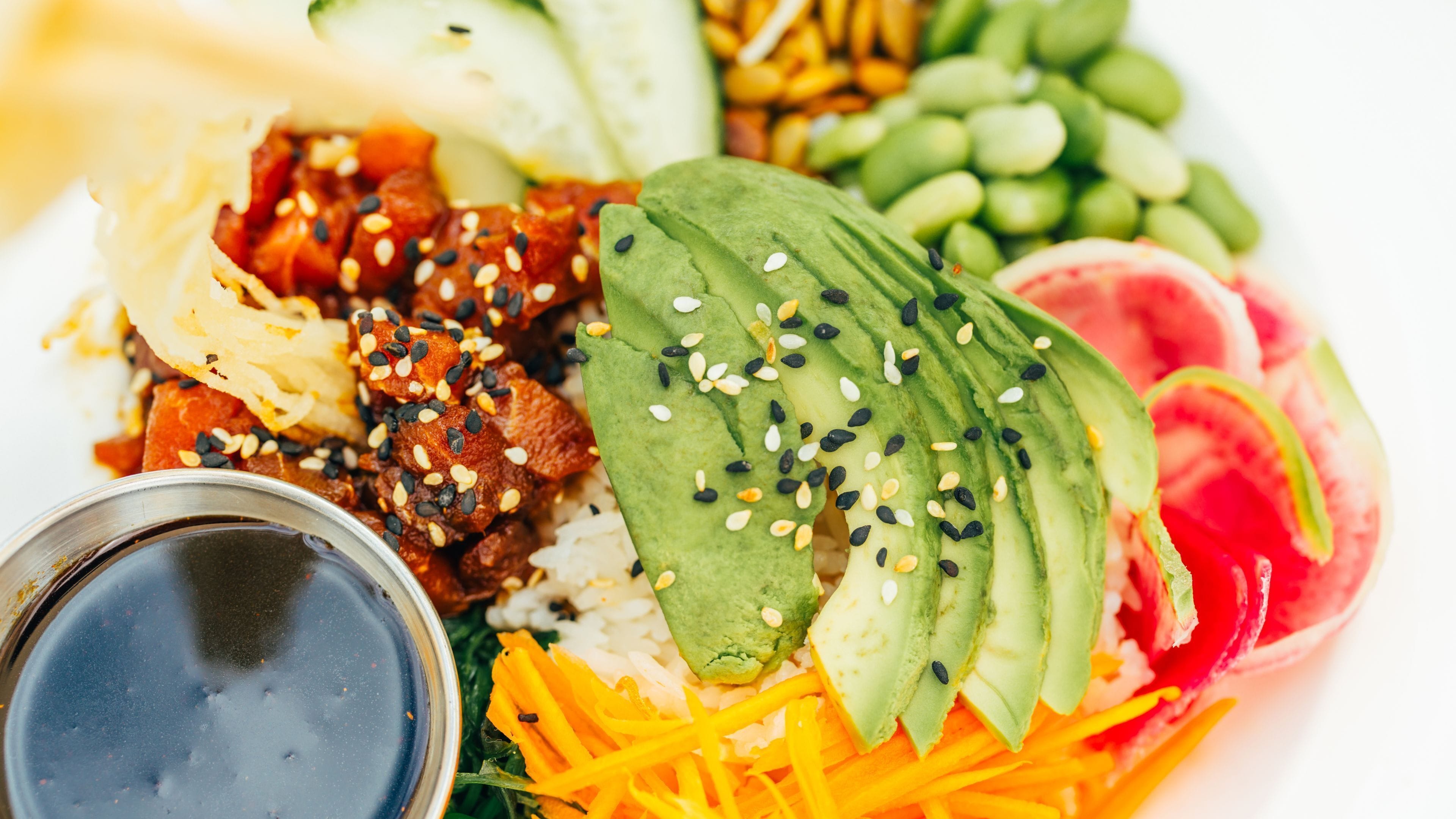 A plate of food with various items including avocado slices, rice, and vegetables.