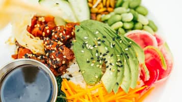 A plate of food with various items including avocado slices, rice, and vegetables.