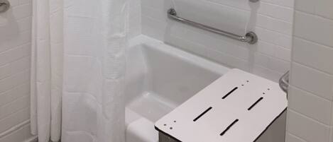 A bathroom with a white bathtub, a shower curtain, and a grab bar installed above the tub.