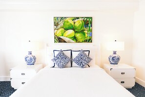 A hotel room with a bed, two nightstands, a vase on each nightstand, and a painting above the bed. - Oceans Edge Key West Resort, Hotel & Marina (Key West)