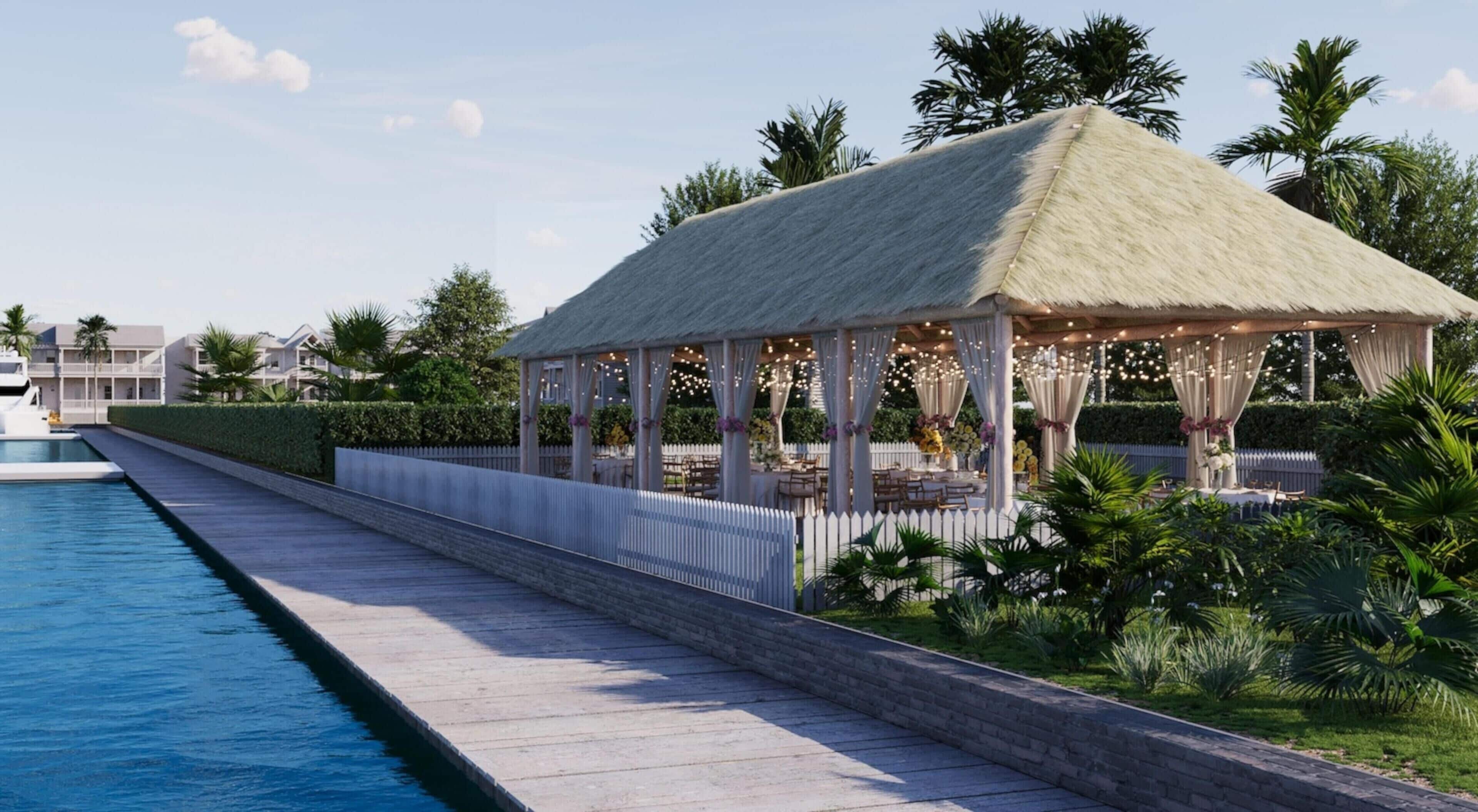 Ein Pavillon am Pool mit einem Reetdach, umgeben von üppiger Vegetation und einem weißen Zaun.