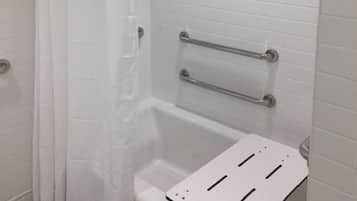 A bathroom with white tiled walls, a shower with a curtain, and a grab bar installed above the bathtub.
