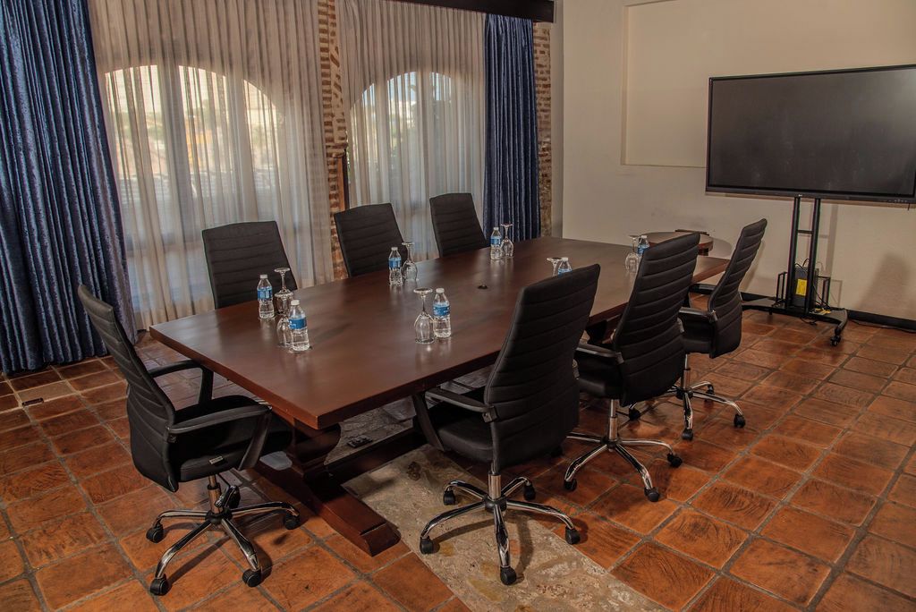 A conference room with a long table, six chairs, and a large screen.