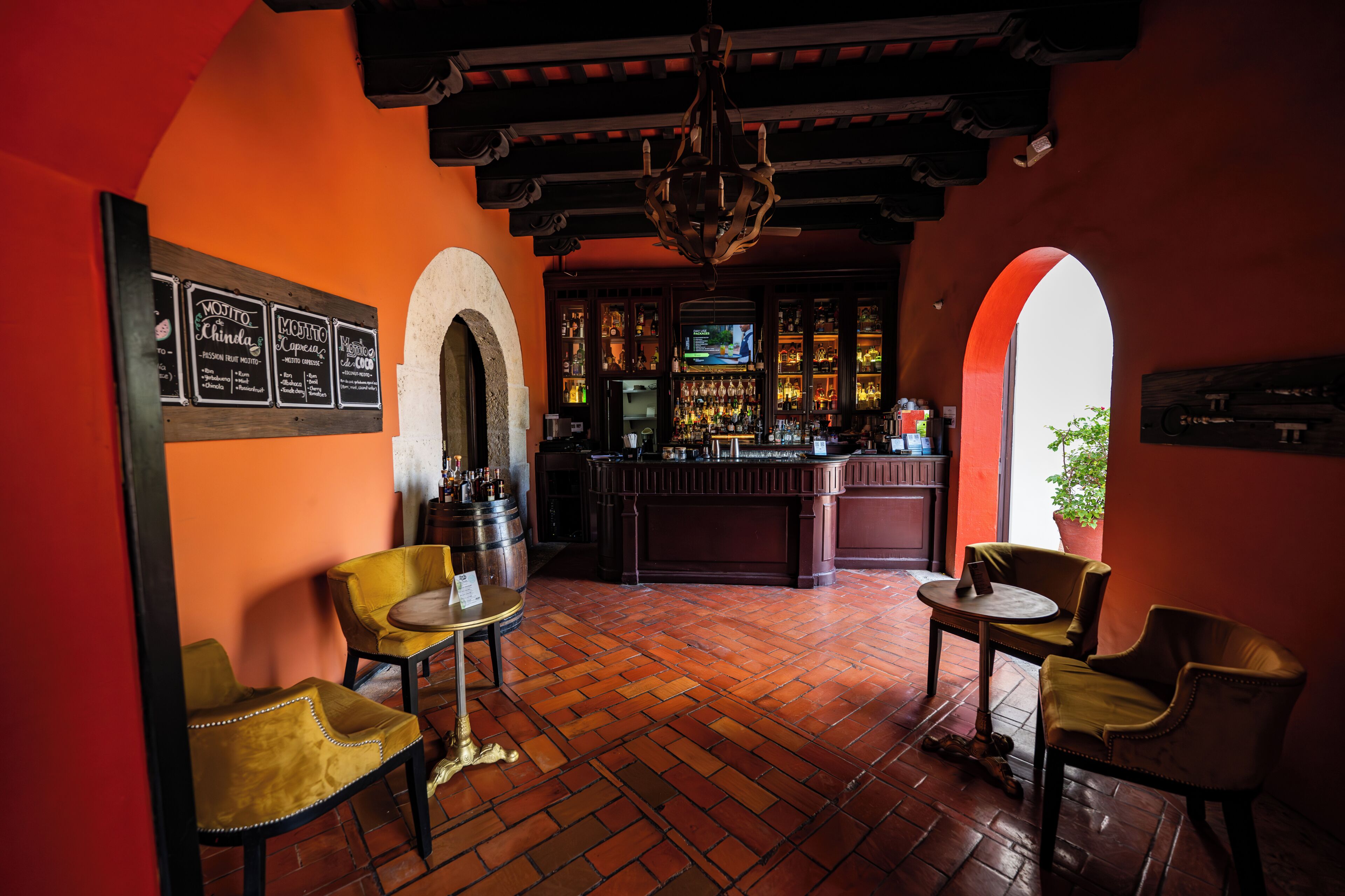 Una zona de bar con suelo de madera, dos mesas redondas y taburetes de bar.
