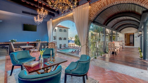 Un área de lounge lujosa con piscina, asientos cómodos y vistas a la ciudad.