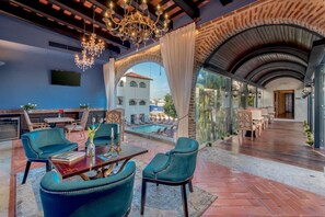 A luxurious lounge area with a pool, comfortable seating, and a view of the city. - Hodelpa Nicolas de Ovando (Santo Domingo)