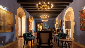 Un pasillo con candelabro, arcos y zonas de estar.