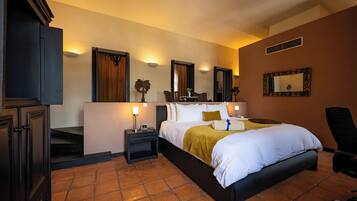 A hotel room with a large bed, two bedside tables, a desk, a chair, and a mirror on the wall.