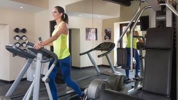 Una palestra con tapis roulant, una panca per pesi e uno specchio.