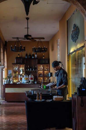 A bar area with a bartender, shelves of bottles, and a sign reading 'LA CAVA'.