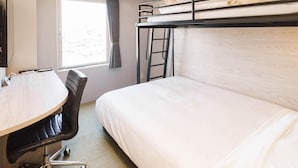 Een hotelkamer met een stapelbed, een bureau met stoel, een raam met gordijnen en een flatscreen televisie.