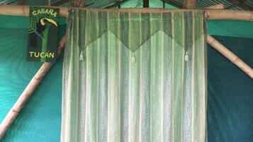 Une porte en métal ondulé à motifs verts et blancs, un cadre de porte en bois et une enseigne illustrée avec un toucan et du texte.