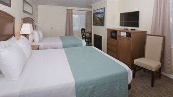 Een hotelkamer met twee bedden, een televisie, een bureau met lamp, een stoel en uitzicht op de omgeving.