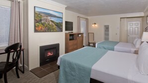 Camera d'albergo con due letti, un camino, un quadro, una televisione e una scrivania.