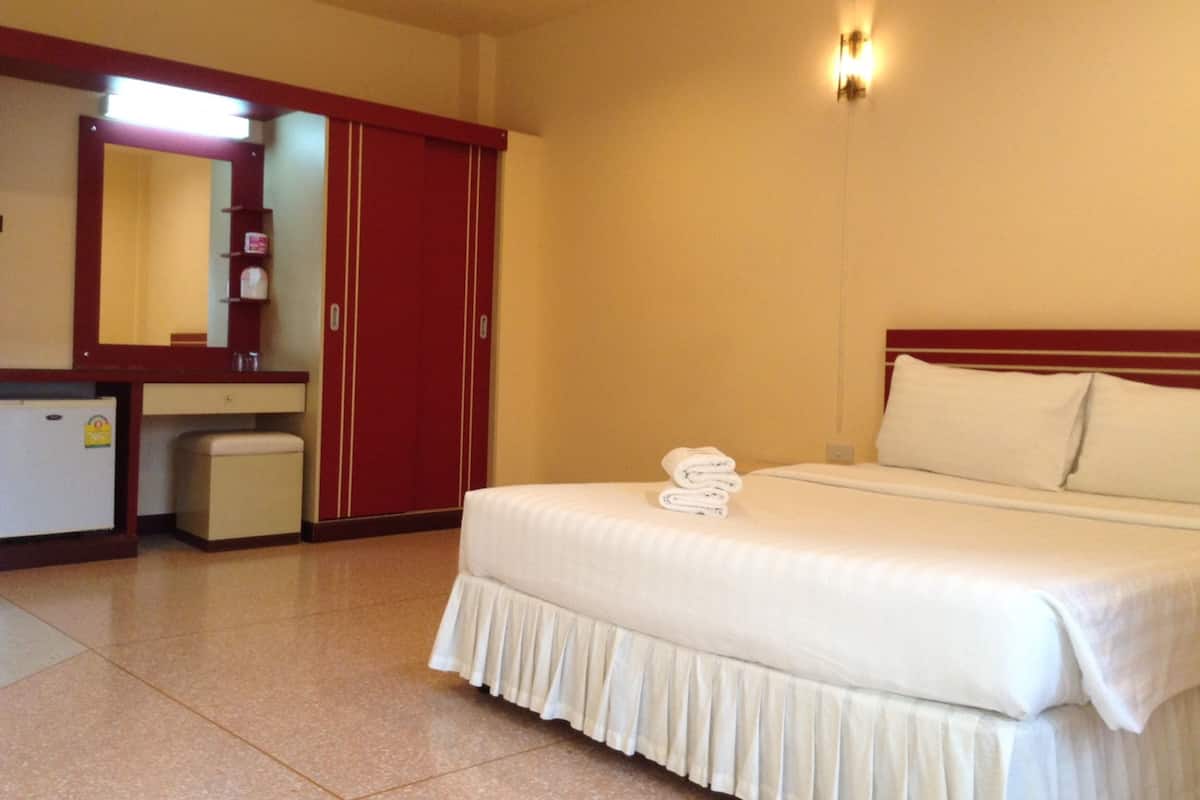 A hotel room with a bed, a desk, a mirror, and a wardrobe.