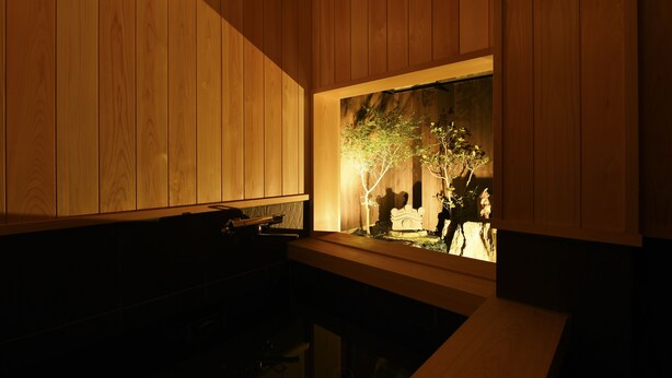 A room with wooden paneling, a small table, and a window with a view of a tree and a statue. - Kuraya Omiya-Shimabara (Kyoto)