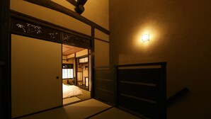 A traditional Japanese room with tatami flooring, a sliding door, and a wall-mounted light fixture. - Kuraya Omiya-Shimabara (Kyoto)