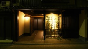 A traditional Japanese building at night with a well-lit entrance and a small garden with bamboo. - Kuraya Omiya-Shimabara (Kyoto)