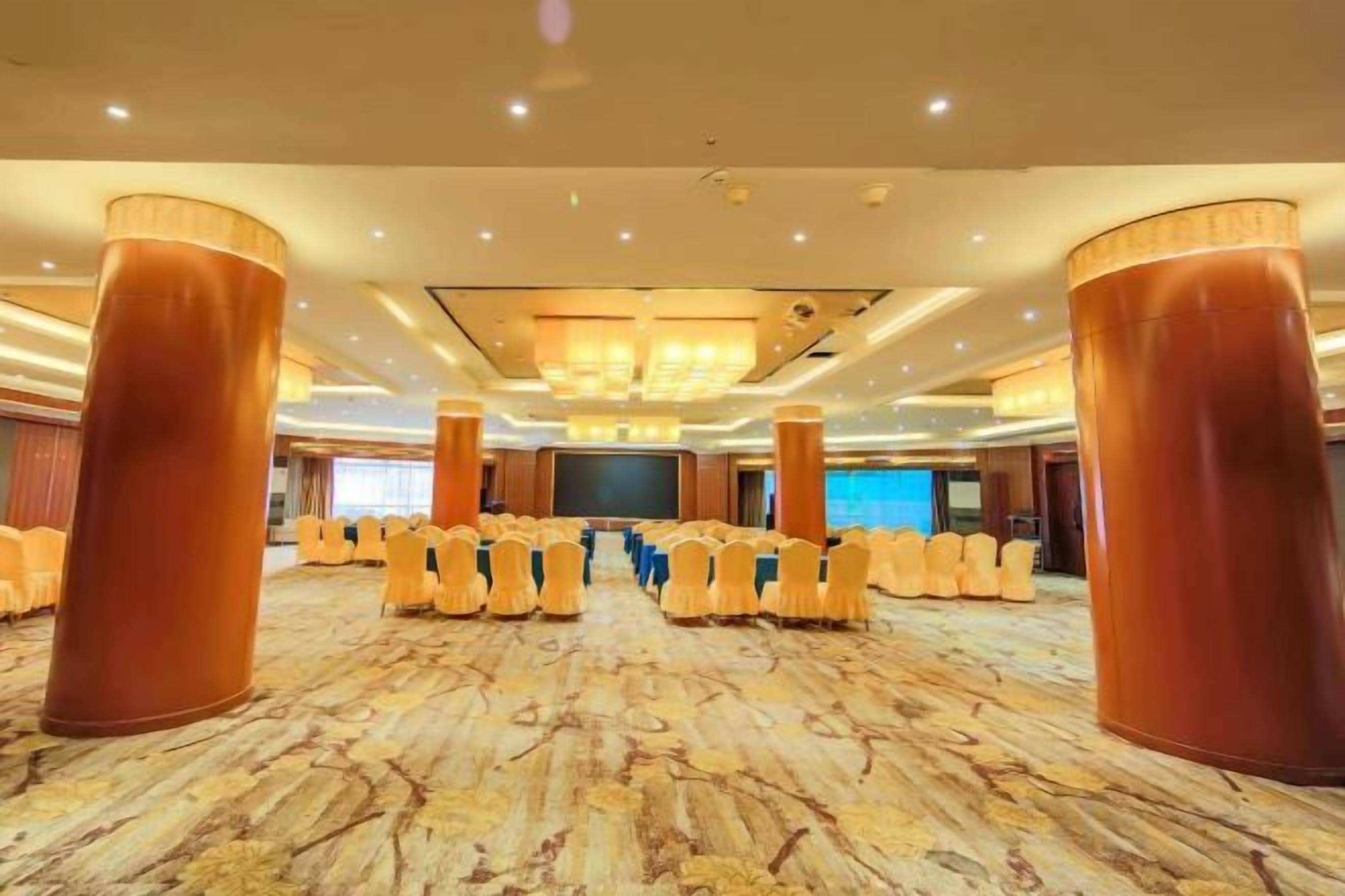 Un salón de conferencias con filas de sillas, una pantalla grande y un atril.