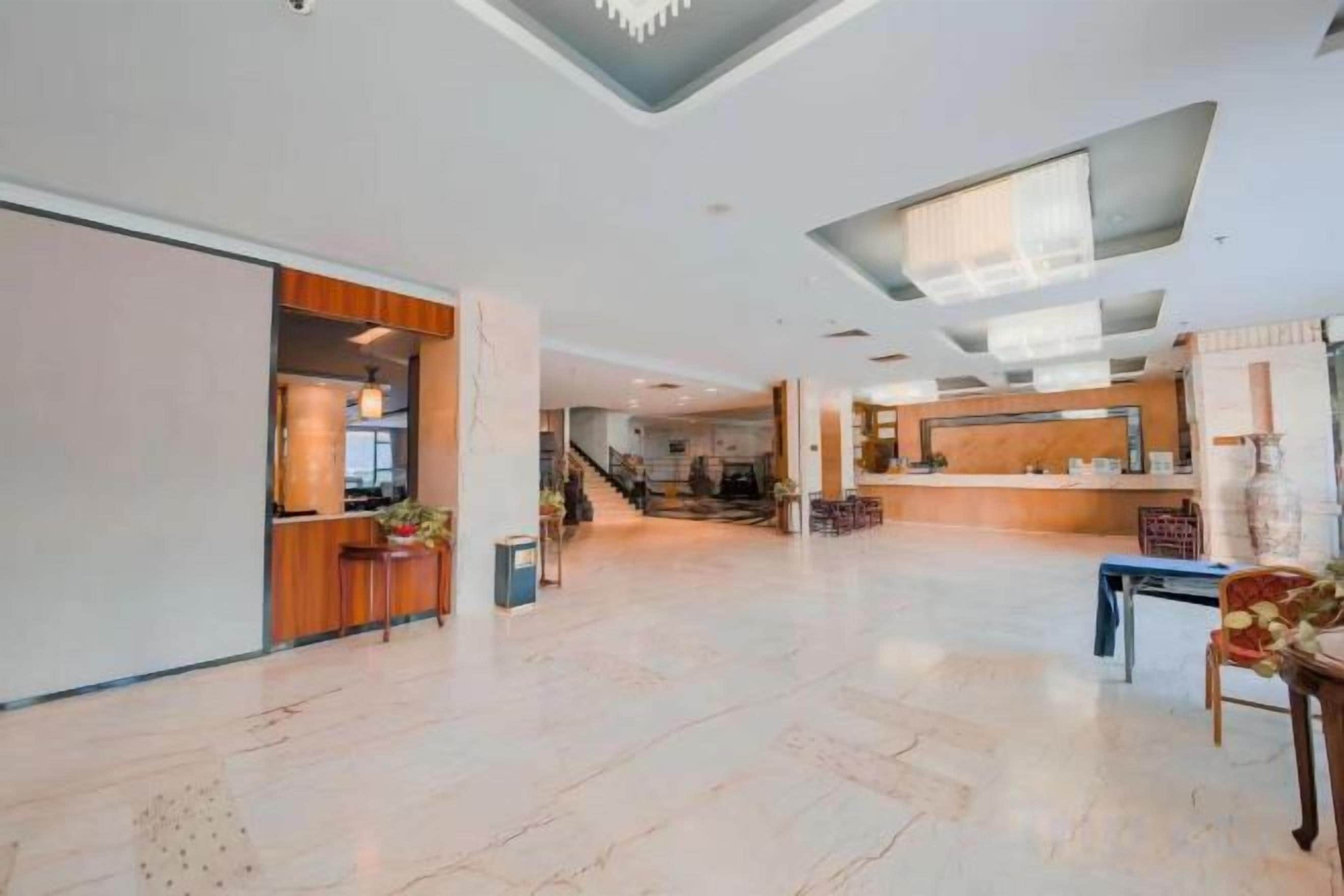 Un hall espacioso con una recepción, una escalera y un comedor.