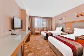 A hotel room with a bed, a desk, a television, and a window with curtains. - Camellia Hotel (Kunming)