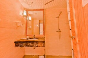 A bathroom with a wooden vanity, a mirror, a shower, and a toilet. - Camellia Hotel (Kunming)