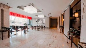 A spacious lobby with a marble floor, a reception desk, and a seating area with tables and chairs. - Camellia Hotel (Kunming)