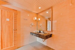 A bathroom with a wooden door, a marble sink, and a large mirror.
