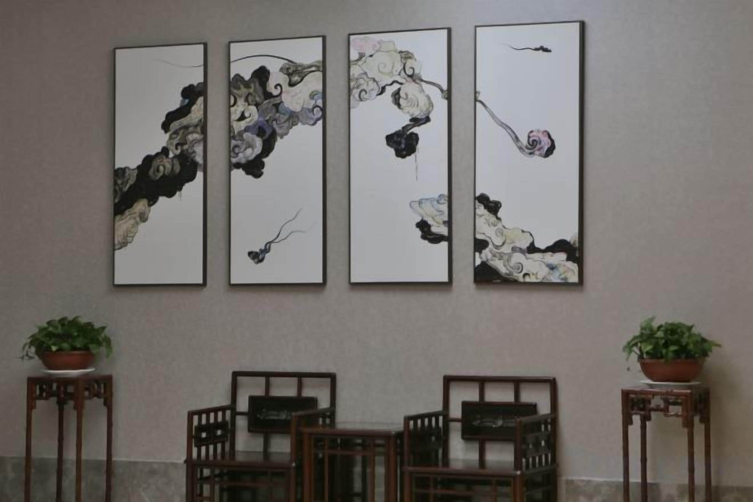 Uma área de refeições com mesa, cadeiras, um quadro na parede e duas plantas em vasos.