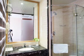 A modern bathroom with a glass-enclosed shower, a marble sink, and a large mirror.