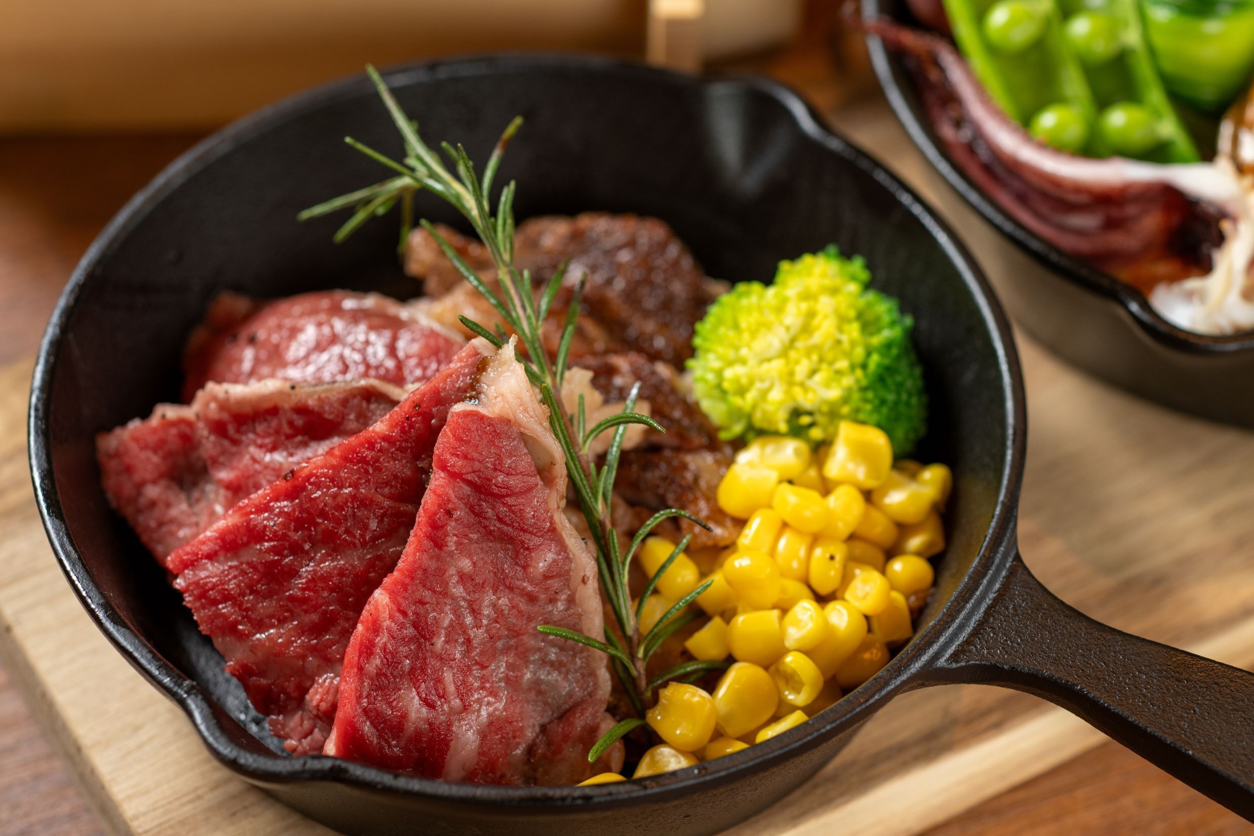 A skillet with steak, corn, and broccoli.