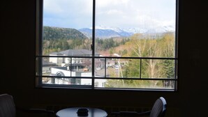 Une pièce dotée d’une grande fenêtre donnant sur une zone boisée et des montagnes.