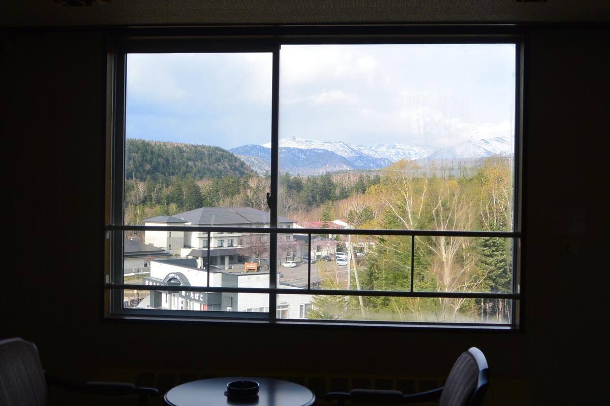 Ein Zimmer mit einem großen Fenster und Blick auf bewaldetes Gebiet und Berge.