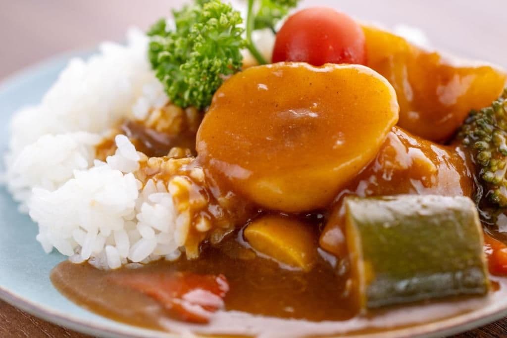 Un plato de comida con arroz, verduras y salsa.
