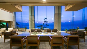 Comedor con una gran mesa y múltiples sillas, con vista a un paisaje marino.