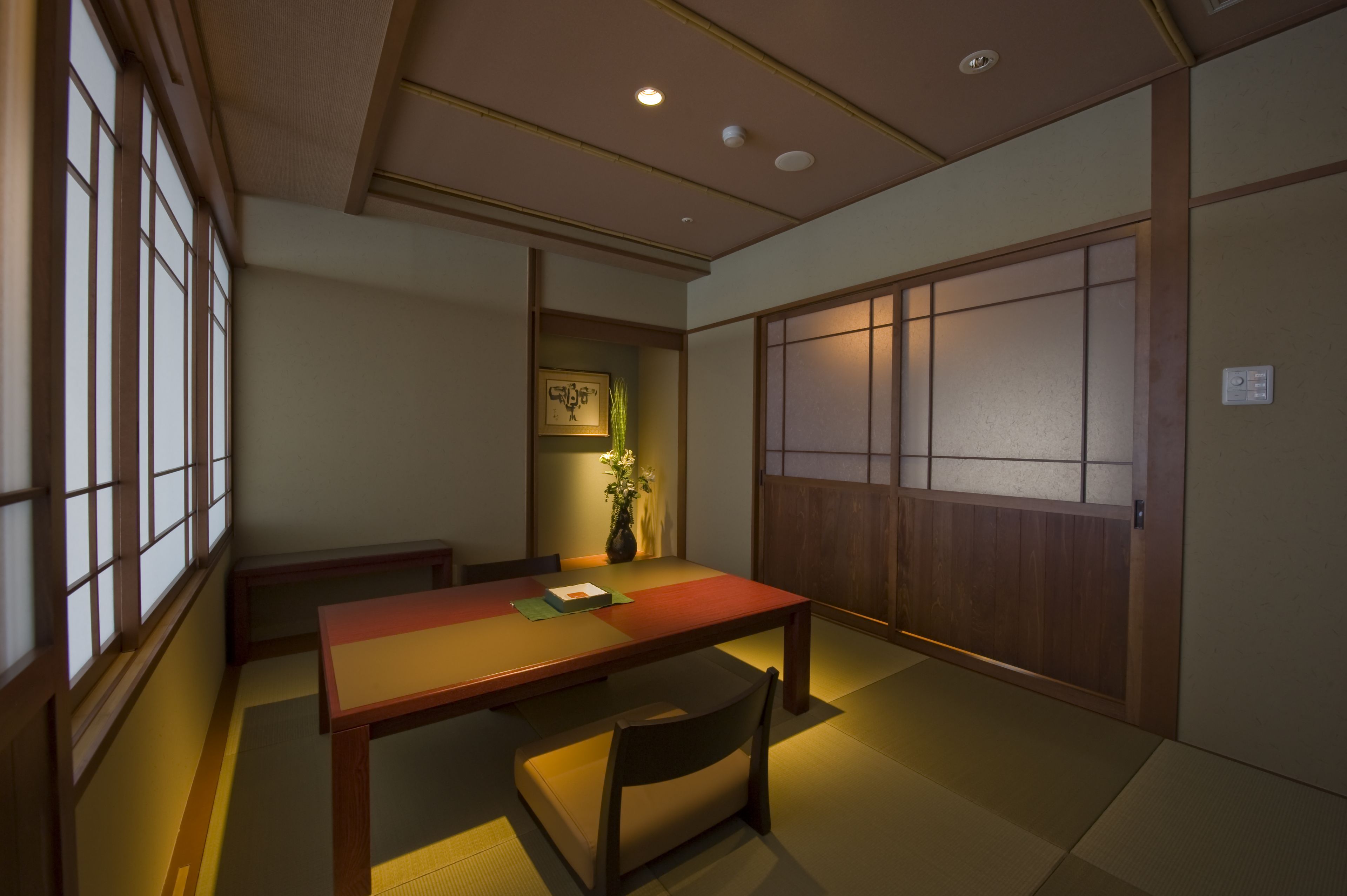 A traditional Japanese room with tatami flooring, a low wooden table, and sliding doors.