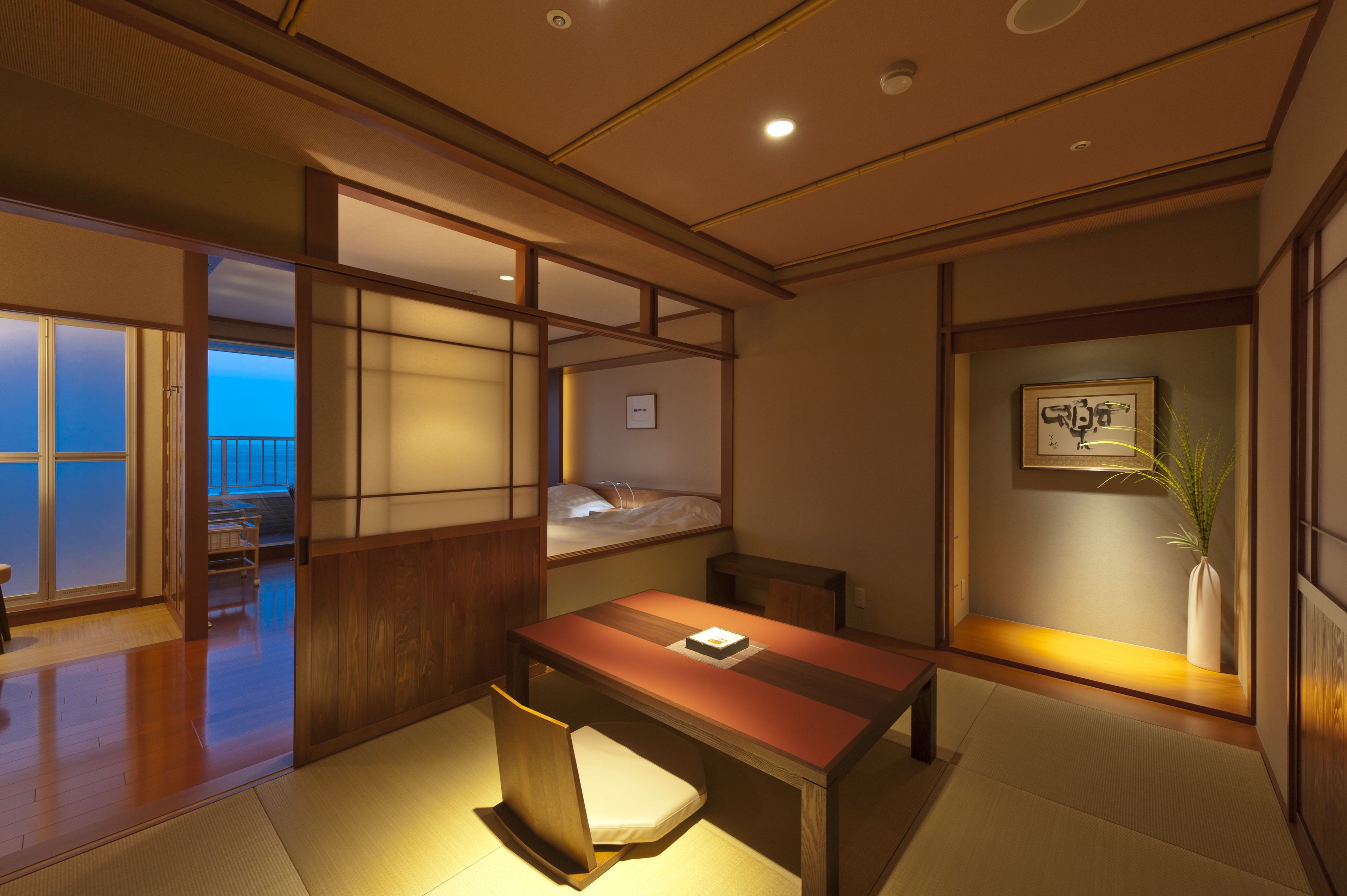 Um quarto em estilo japonês tradicional, com tatames, uma mesa de madeira baixa, uma poltrona acolchoada e uma cama com futon.
