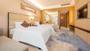 A hotel room with two beds, a TV, a desk, and a bathroom visible through a glass door. - Shuidu Holiday Hotel (Shenzhen)
