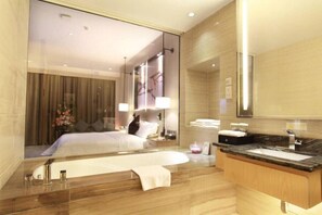 Una habitación de hotel moderna con una cama grande, un tocador de madera con un lavabo y un espejo amplio.