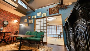 Une pièce de style japonais traditionnel, avec un sol recouvert de tatamis, un canapé vert, une table en bois et une porte coulissante en papier de riz (shoji).