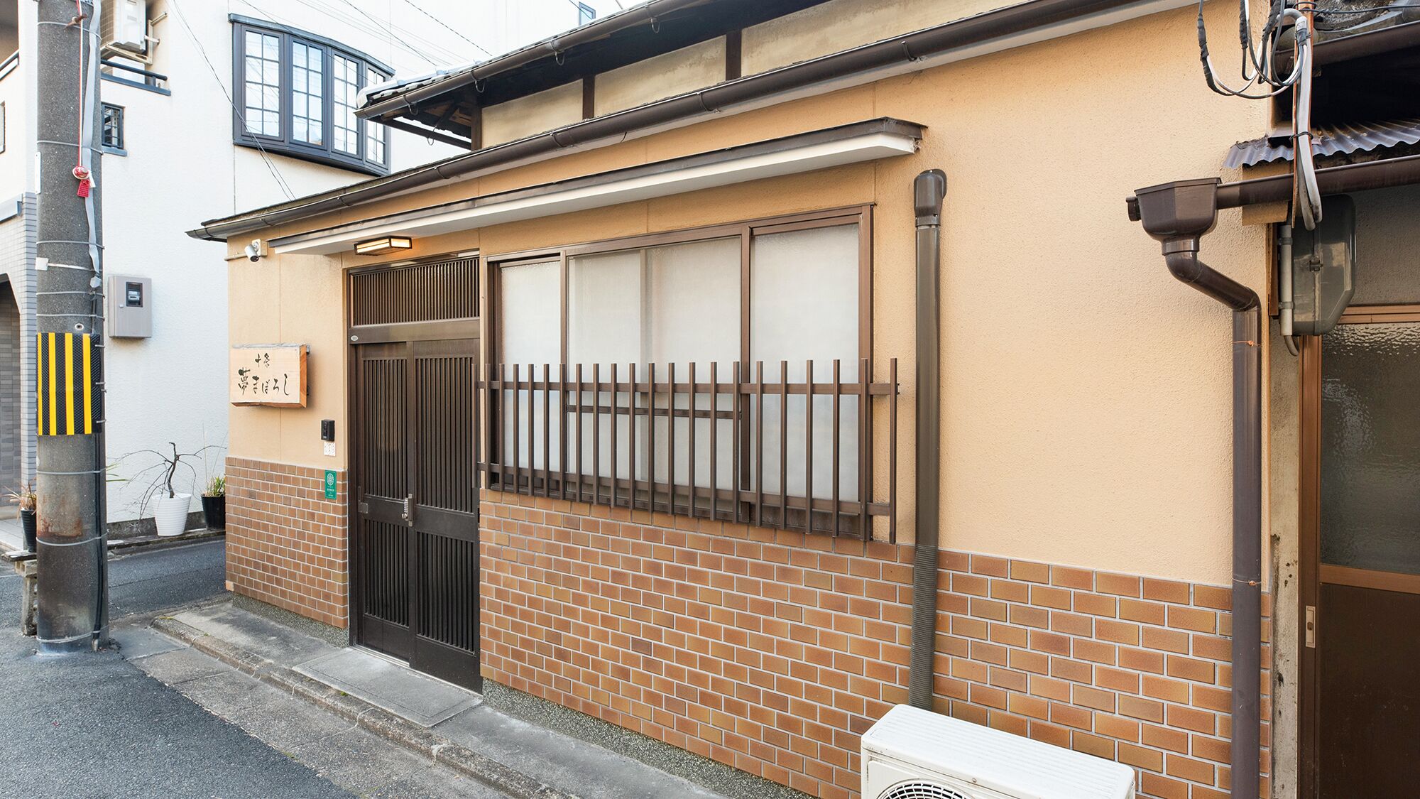 A building with a brick facade, a metal gate, and a window with bars.