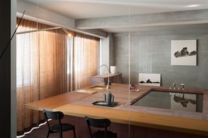 A modern kitchen with a wooden countertop, two black chairs, a sink, and a glass backsplash. - Bijuu (Kyoto)