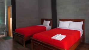 A room with two wooden beds, each with a red bedspread and white pillows. The room has a brick wall and a wooden floor. - Istana Petani Hotel (Sukapura)