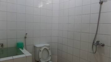 Un baño pequeño con azulejos blancos, inodoro, ducha y dispensador de pañuelos verdes.
