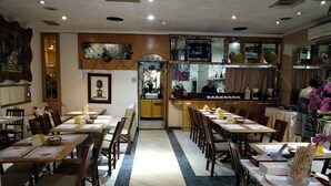 A restaurant with multiple dining tables and chairs, a kitchen area, and a decorative wall with a 'PEACE' sign.